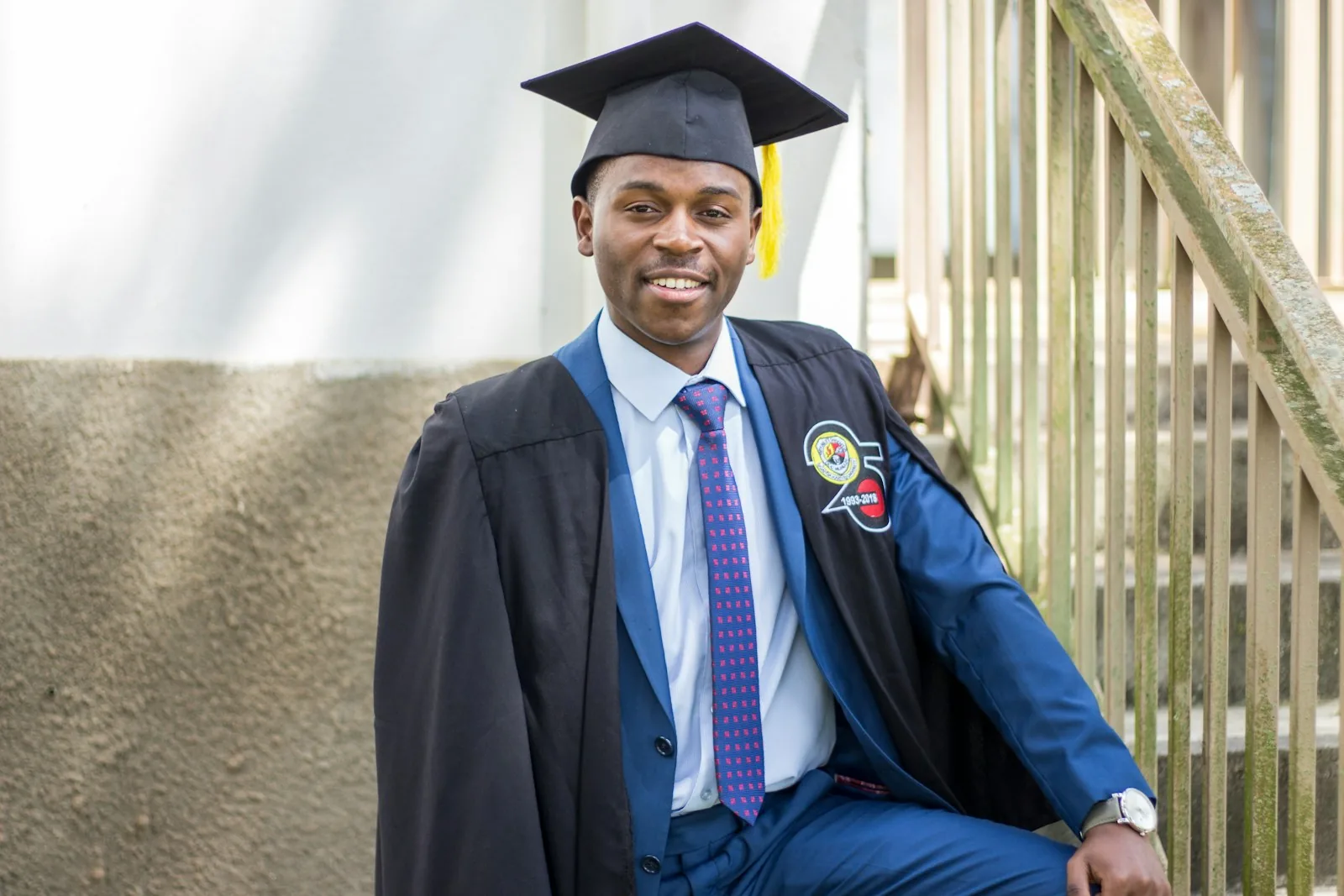A graduate in cap and gown on the steps after his ceremony